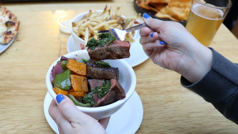 A hand scooping a piece of steak out of a bowl of steak bites.